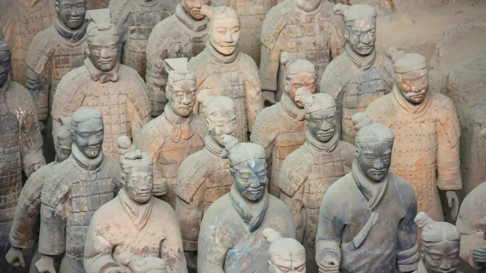 Ranks of life-size terracotta warriors standing in the excavation pit, each with an individually modelled face, in warm earthen light